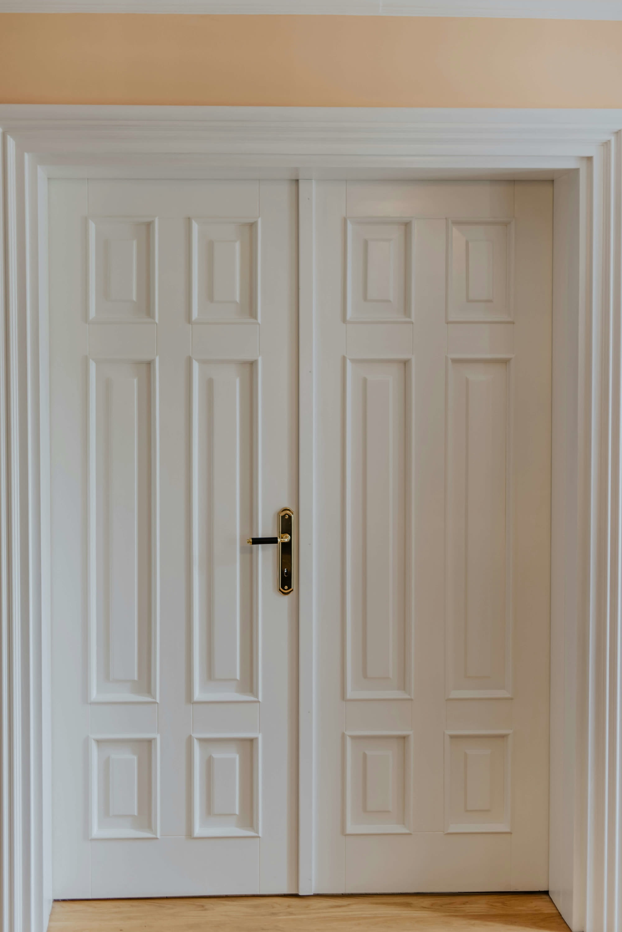 A white six-panel solid wood door with a brass lever, set in its casing
