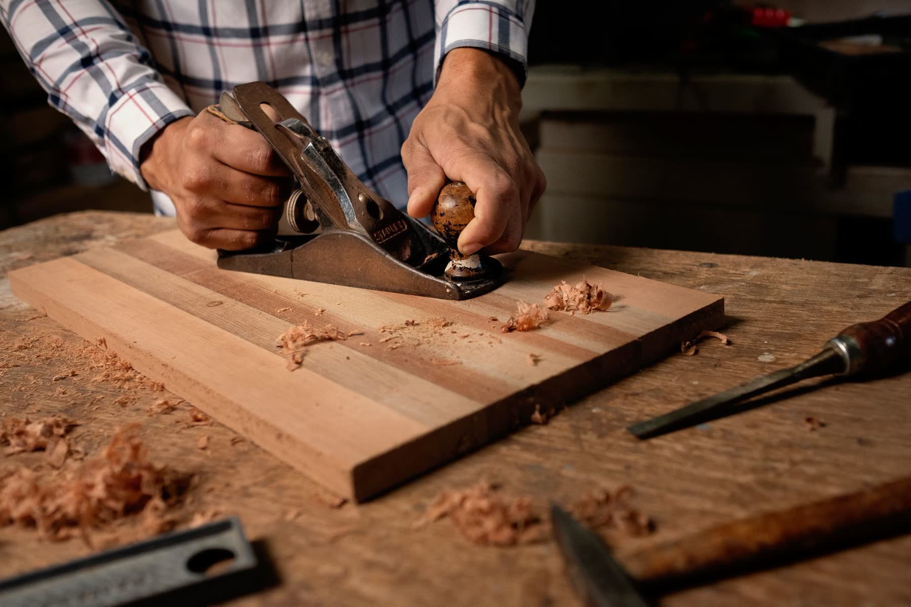 Hands smoothing a board on a workbench
