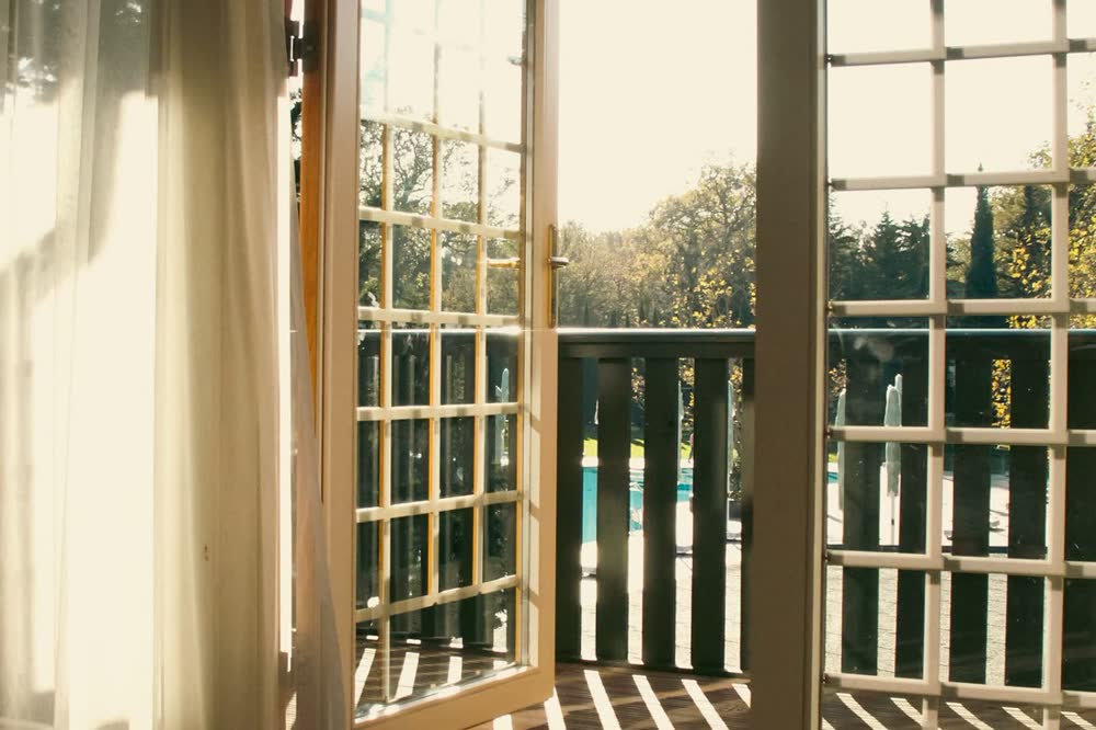 French door standing open onto a sunlit balcony