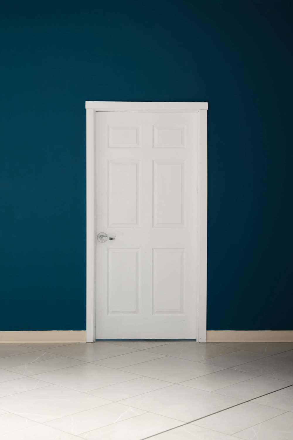 White six-panel door framed by casing on a dark blue wall