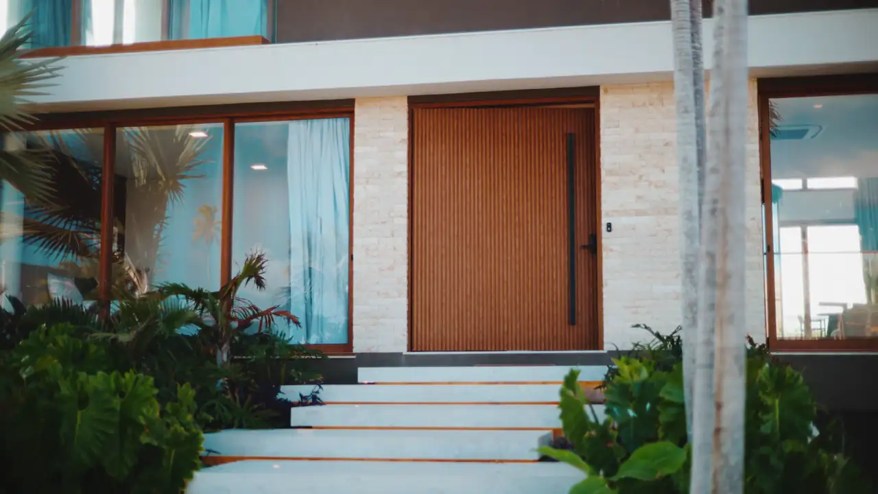 A tall solid wood pivot door at a modern home entrance